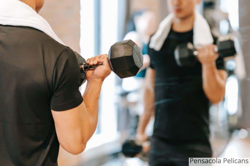 Crop man working out with weights in gym